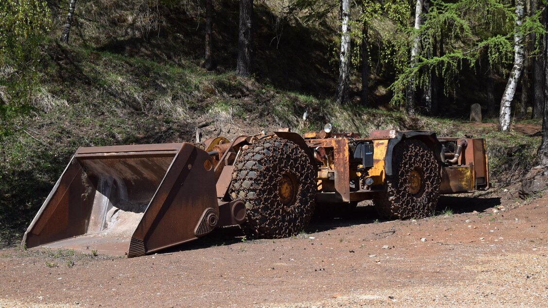 Ein alter Baukran steht in einem bewaldeten Gebiet. Der Kran ist mit Erde und Dreck bedeckt und scheint nicht in Benutzung zu sein. | © Abenteuer Erzberg