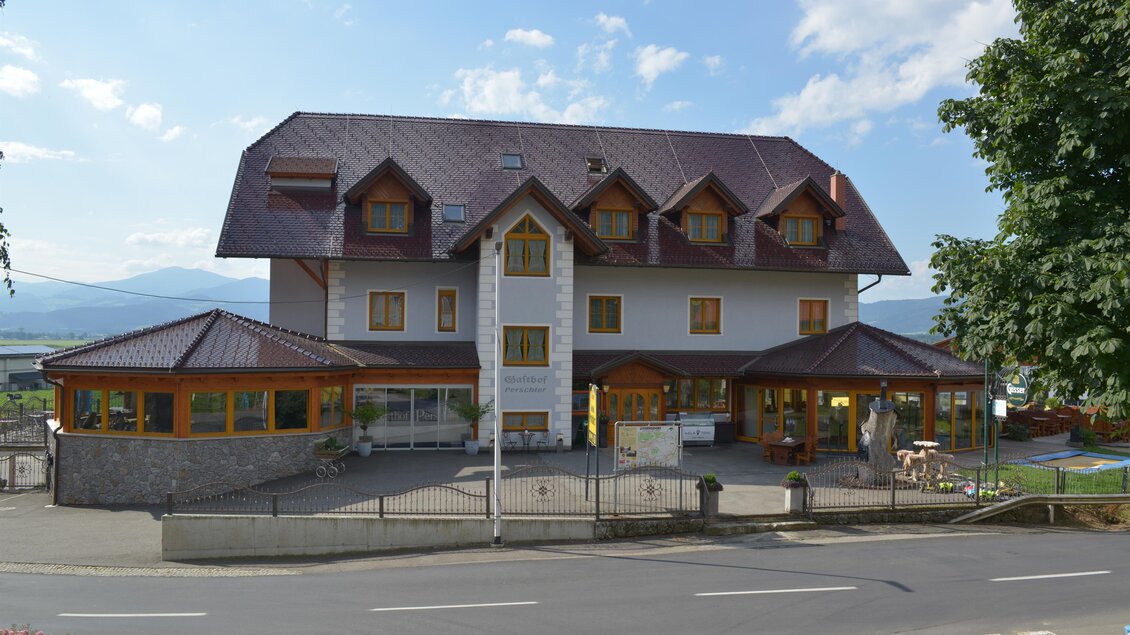 Ein charmantes Hotelgebäude mit einem modernen Dach und großen Fenstern. Umgeben von einer malerischen Landschaft, zeigt es ein einladendes Ambiente für Gäste. | © Hotel-Restaurant Perschler