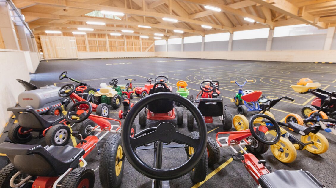 Viele bunte Kinderfahrzeuge stehen auf einem großen Innenbereich mit einer Fahrbahn. Die Umgebung ist hell und einladend, ideal für Spiel und Spaß. | © www.zloam.at