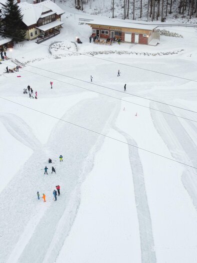 A snowy area with several skiers and ice skaters. In the background, buildings and trees can be seen. | © Gemeinde Wald am Schoberpaß