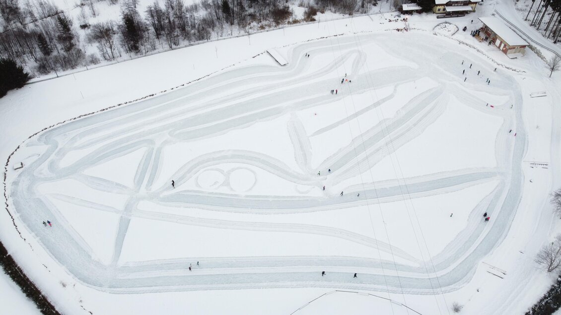 Eine offene Eisfläche mit vielen Schlittschuhläufern. Die Wege sind kunstvoll in den Schnee geritzt. | © Gemeinde Wald am Schoberpaß