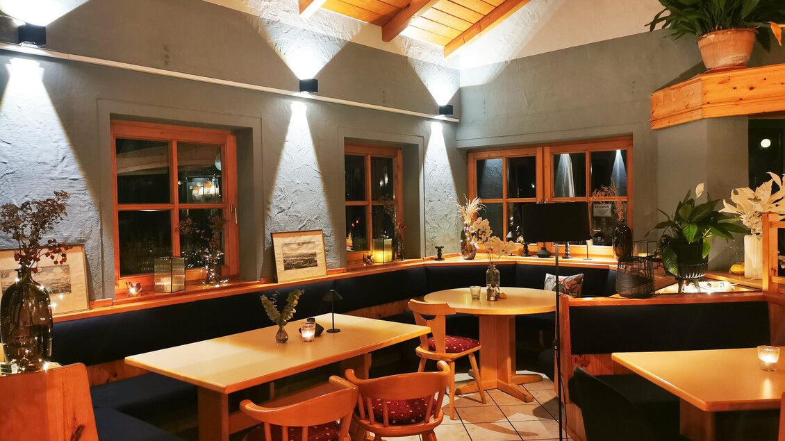 Ein gemütliches Restaurant mit Holzdecke und Sanftbeleuchtung. Die Tische sind mit Pflanzen dekoriert und das Ambiente ist einladend. | © Magda-Rosa Schuster