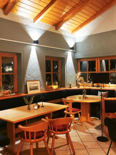 Ein gemütliches Restaurant mit Holzdecke und Sanftbeleuchtung. Die Tische sind mit Pflanzen dekoriert und das Ambiente ist einladend. | © Magda-Rosa Schuster