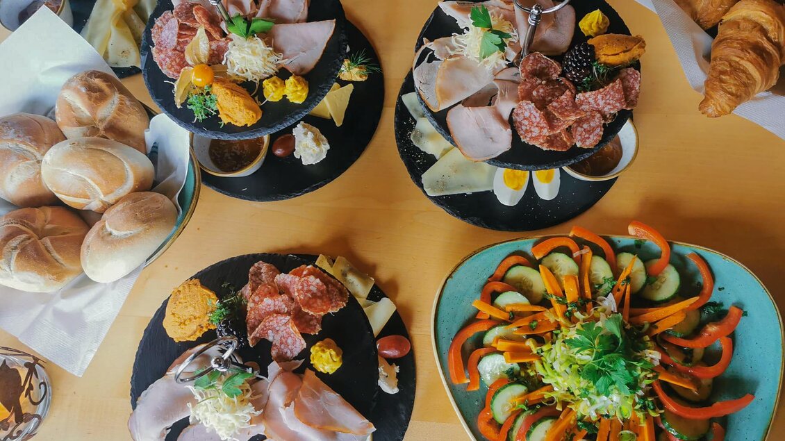 Ein reichhaltiges Frühstücksbuffet mit verschiedenen Aufschnittplatten, Käse und frischem Gemüse. Dazu gibt es Brötchen und Croissants, die den Tisch bereichern. | © Schuster Kulinarik OG
