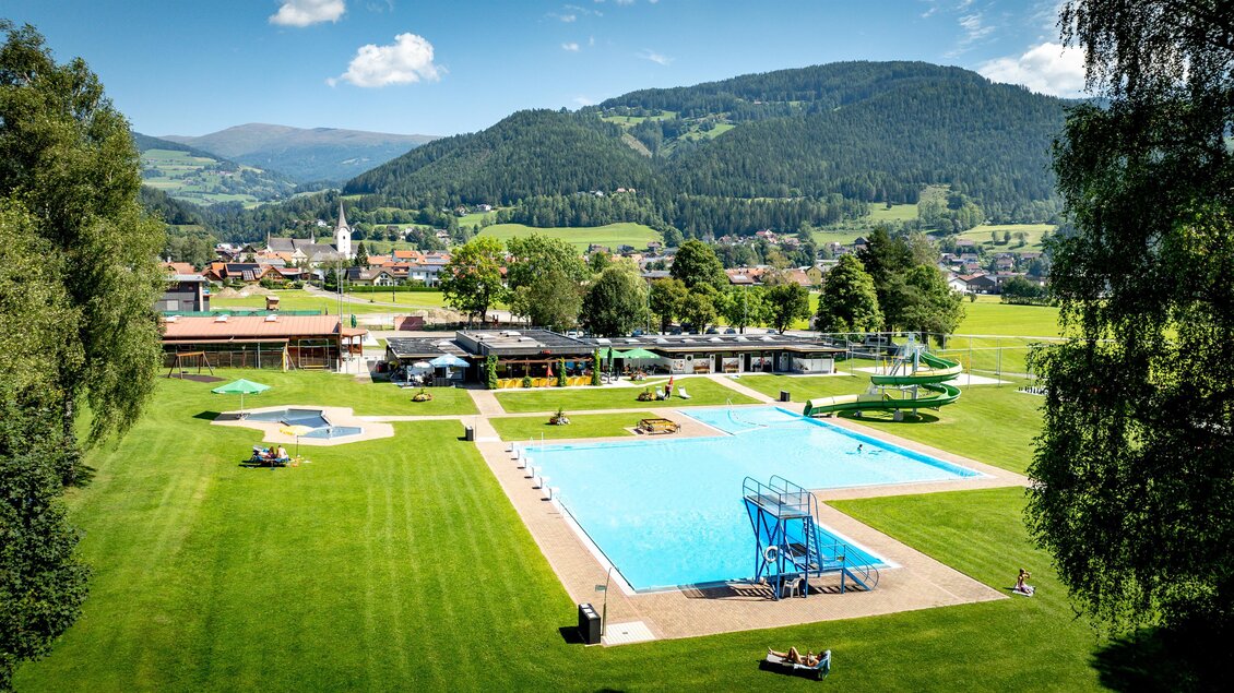 Ein schöner Außenpool mit Rasenflächen und Spielgeräten. Die Umgebung ist von Bergen und grünen Bäumen umgeben. | © TV Murau