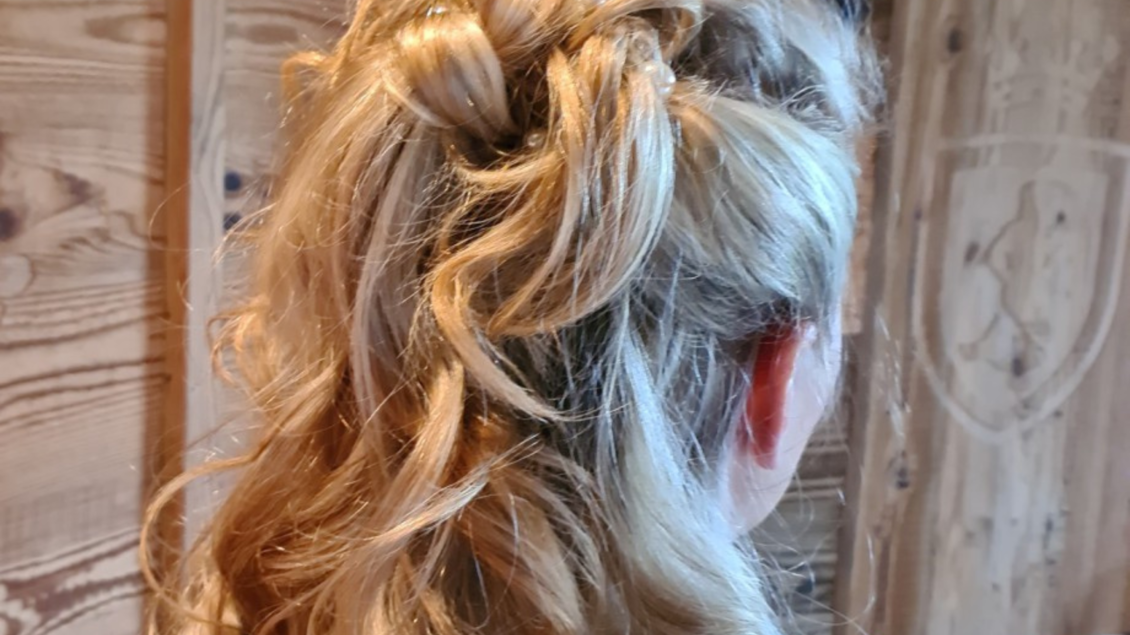 Eine schöne Haarfrisur mit lockigen Strähnen, die elegant arrangiert sind. Der Hintergrund ist aus Holz. | © Frisiersalon Scherenzauber