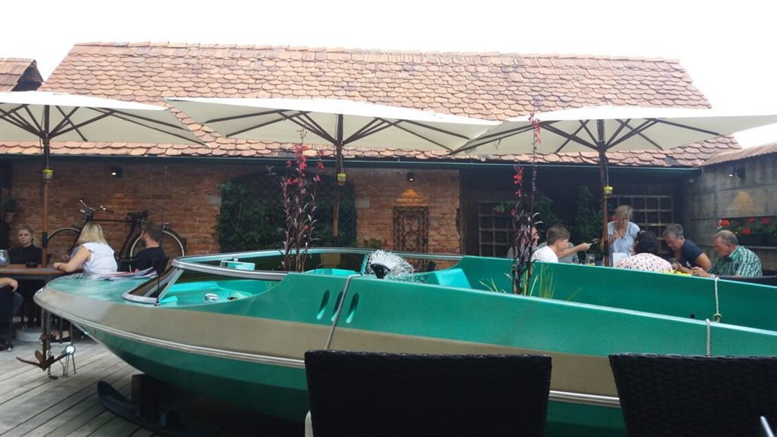 Ein Restaurant mit Booten als Dekoration und Sonnenschirmen. Die Gäste genießen ihre Zeit in einer gemütlichen Atmosphäre. | © TV Lipizzanerheimat/EU