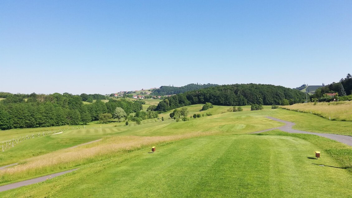 Eine grüne Golfanlage mit sanften Hügeln und klarem blauen Himmel. Die Landschaft ist ruhig und einladend. | © TV- Thermen- & Vulkanland