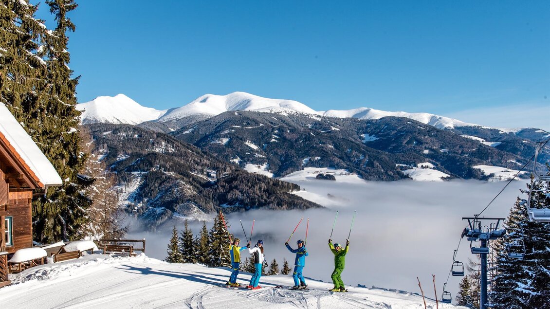 Eine Gruppe von Skifahrern steht auf einem schneebedeckten Hang und jubelt. Im Hintergrund sind Berge und ein klarer Himmel zu sehen. | © Gaaler Lifte
