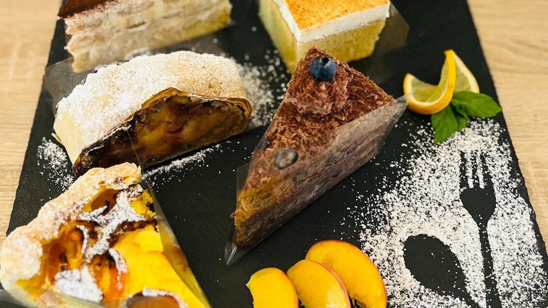 Eine Auswahl an leckeren Kuchen auf einem schwarzen Servierteller. Die Kuchen sind mit Puderzucker und frischen Früchten dekoriert. | © Gasthaus Ägydi