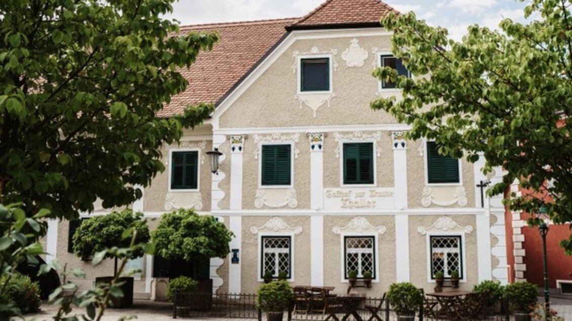 Ein charmantes Haus mit einer hellen Fassade und grünen Fenstern. Umgeben von Bäumen und Sträucher, bietet es eine einladende Atmosphäre. | © GH Thaller