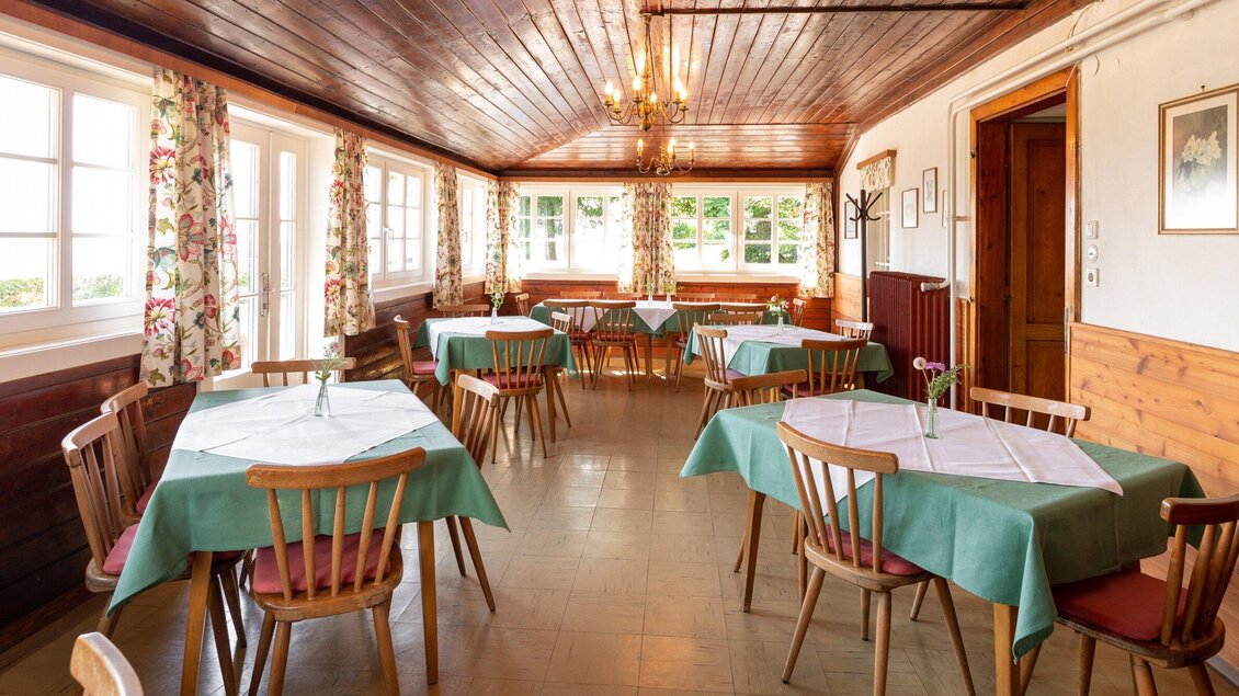 Ein gemütlicher Speisesaal mit Tischen in pastellgrünem Tischtuch. Große Fenster sorgen für viel Tageslicht und eine einladende Atmosphäre. | © TV Region Graz - Harry Schiffer
