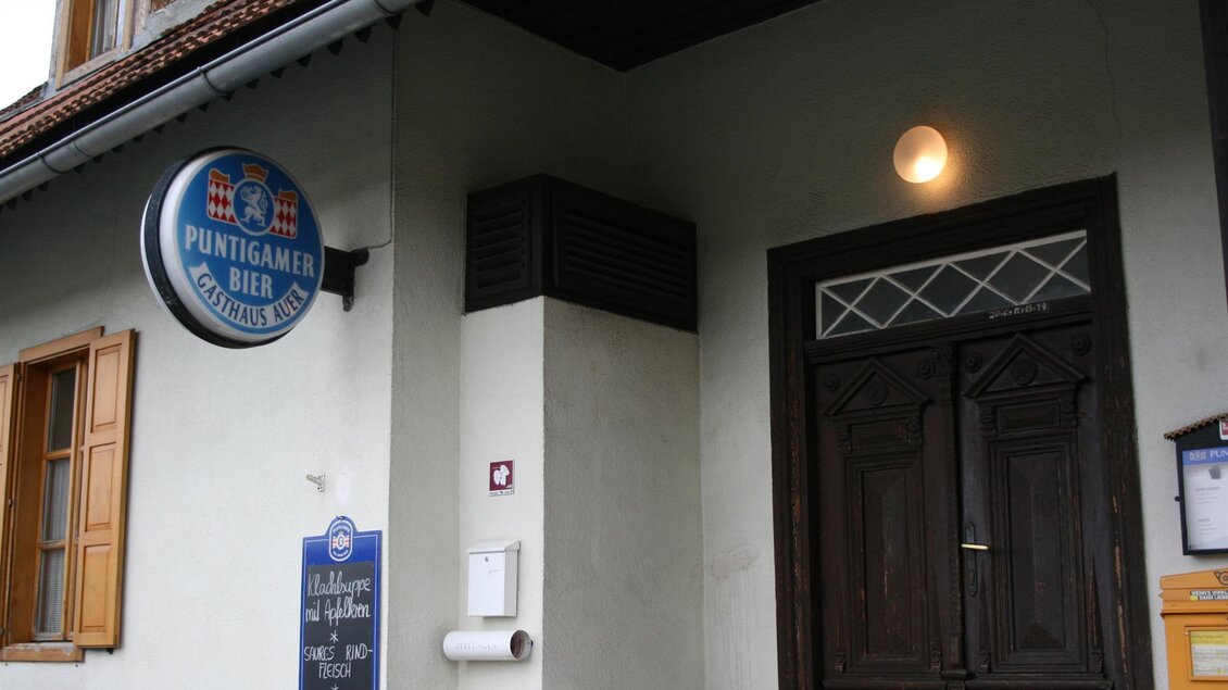 Eine gemütliche Gaststätte mit einem Holzstuhl und einer rustikalen Tür. Das Schild zeigt die Brauerei Puntigamer Bier an. | © Schilcherland Steiermark