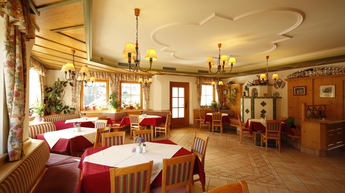 Ein gemütliches Restaurant mit holzvertäfelten Wänden und dekorativen Pflanzen. Die Tische sind mit roten Tischdecken gedeckt und es gibt eine einladende Atmosphäre. | © Herbert Raffalt