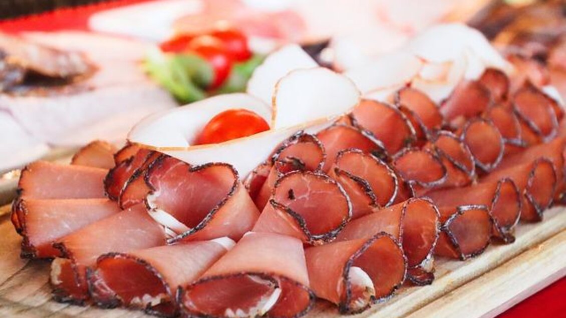 Eine Platte mit hochwertigem Aufschnitt, darunter Schinken und andere Fleischsorten. Auf der Seite sind frische Tomaten und Gemüse zu sehen. | © Pixabay