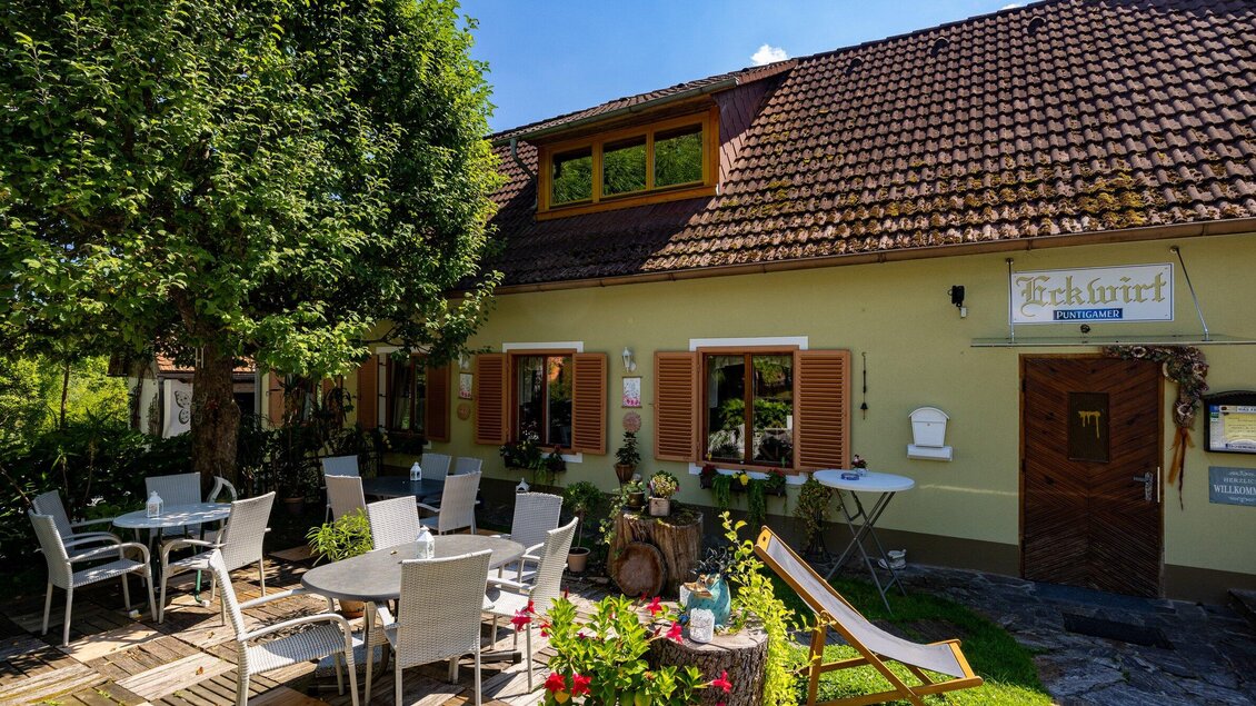 Ein gemütliches Café mit einem einladenden Außenbereich. Tische und Stühle stehen unter den Bäumen vor einem charmanten Gebäude. | © TV Region Graz-Harry Schiffer