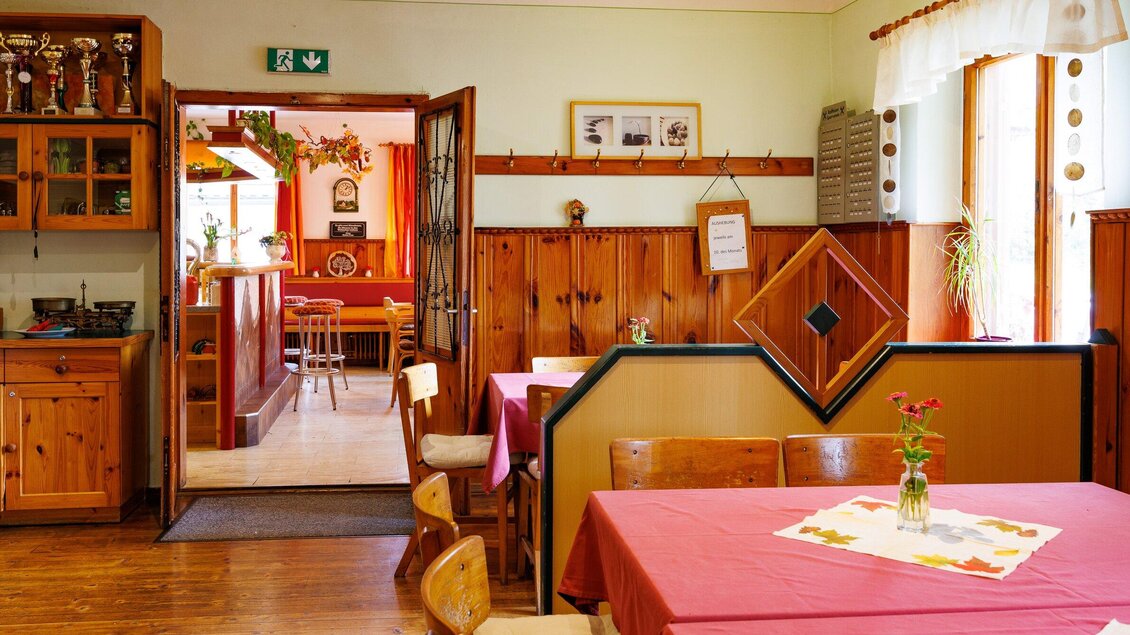 Ein gemütliches Restaurant mit Holzvertäfelungen und roten Tischen. Im Hintergrund sind Sitzplätze und eine einladende Atmosphäre zu sehen. | © TV Region Graz-Harry Schiffer