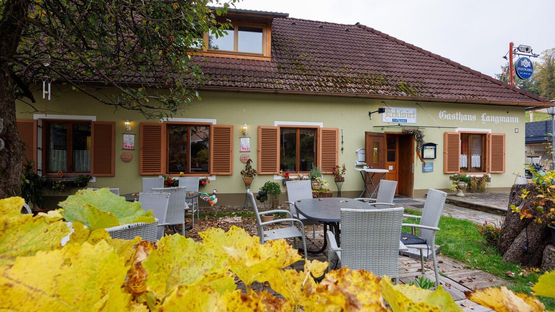 Ein charmantes Gasthaus mit Fensterläden und einem gemütlichen Außenbereich. Bunte Herbstblätter umgeben die Terrasse. | © TV Region Graz-Harry Schiffer