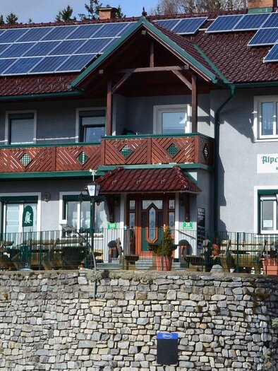 Ein modernes Gebäude mit Solarpanelen auf dem Dach. Vor dem Haus gibt es eine Terrasse mit Pflanzen und Sitzmöglichkeiten. | © Eckwirt-Steirer