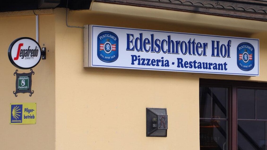 Ein Restaurant mit dem Namen "Edelschrotter Hof" wird angezeigt, das auch als Pizzeria fungiert. Darüber hinaus ist ein Segafredo-Schild sichtbar. | © Steirische Rucksackdörfer
