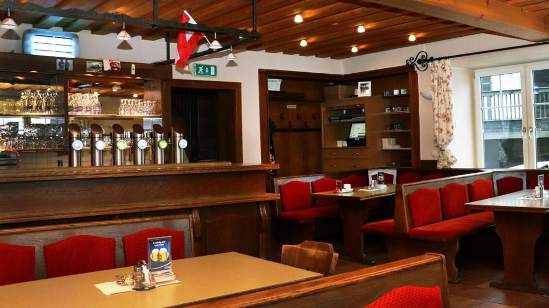 Ein gemütliches Restaurant mit Holztischen und roten Polstersitzen. An der Bar stehen mehrere Zapfhähne für Getränke bereit. | © Steirische Rucksackdörfer
