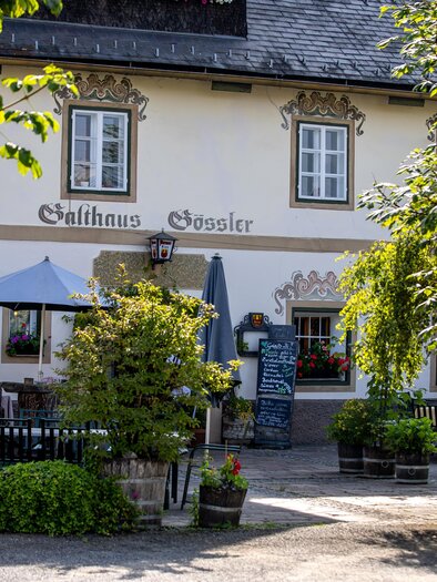 Ein charmantes Gasthaus mit einem einladenden Außenbereich. Umgeben von Bäumen und Blumen, bietet es Platz zum Entspannen. | © Tourismusverband Murau