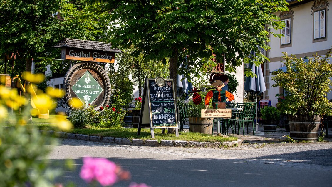 Ein einladendes Restaurant mit einem gemütlichen Außenbereich und bunten Blumen. Ein Schild weist auf das Lokal hin und ein freundlicher Wirt steht bereit, die Gäste willkommen zu heißen. | © Tourismusverband Murau