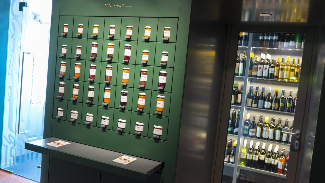 Eine moderne Weinbar mit einer Präsentationswand von Weinen in verschiedenen Flaschen. Auf der rechten Seite ist ein Kühlschrank mit weiteren Weinen sichtbar. | © Werner Krug