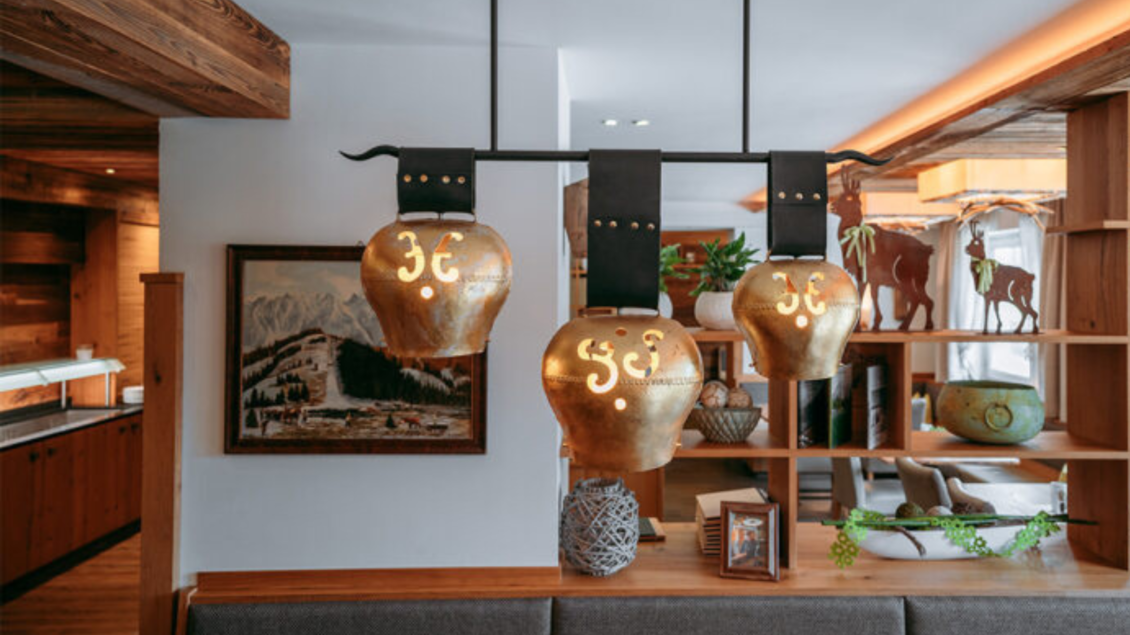 Ein stilvolles Restaurant mit goldenen Hängeleuchten und rustikalen Holzelementen. Im Hintergrund sind dekorative Elemente und Kunstwerke zu sehen. | © Gasthaus Kanzler