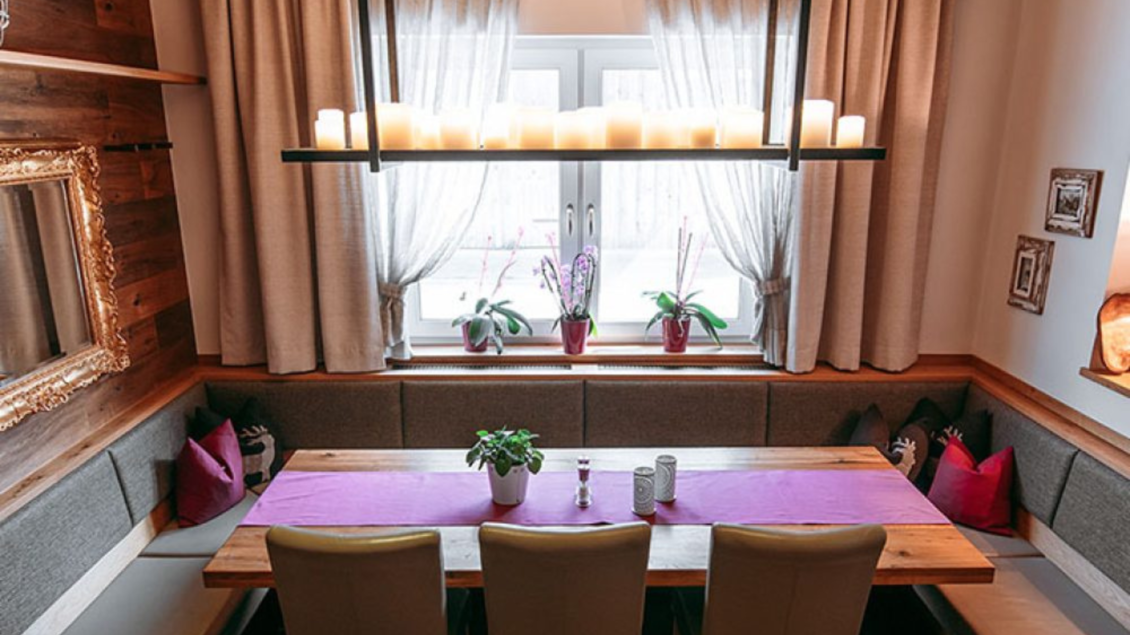 Ein gemütlicher Essbereich mit einem langen Holztisch und Sitzbänken. Große Fenster lassen viel Licht herein, und die Dekoration sorgt für eine einladende Atmosphäre. | © Gasthaus Kanzler
