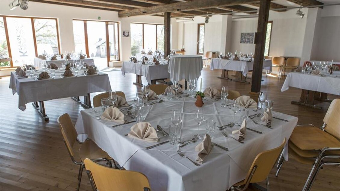 Ein eleganter Speisesaal mit mehreren gedeckten Tischen. Die Tische sind mit weißen Tischdecken und Besteck dekoriert, um eine festliche Atmosphäre zu schaffen. | © Familie Koschak