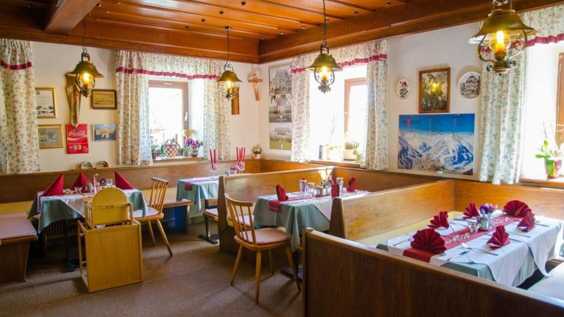 Ein gemütliches Restaurant mit Holzdekor und traditioneller Einrichtung. Die Tische sind elegant gedeckt mit roten Servietten und Kerzen. | © GH Langreiter
