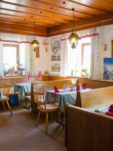 Ein gemütliches Restaurant mit Holzdekor und traditioneller Einrichtung. Die Tische sind elegant gedeckt mit roten Servietten und Kerzen. | © GH Langreiter