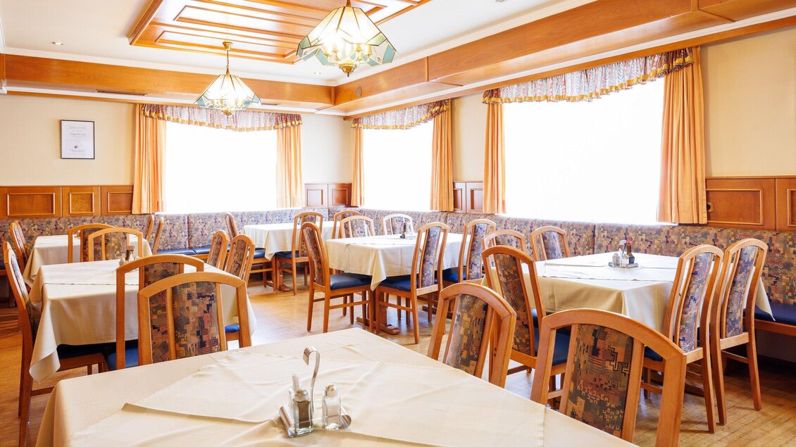 Ein heller, einladender Restaurantbereich mit Holztischen und -stühlen. Die Fenster lassen viel Tageslicht herein und die Wände sind in warmen Farben gestaltet. | © TV Region Graz - Harry Schiffer