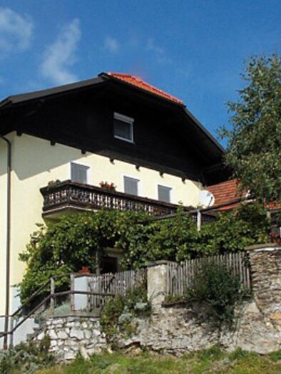 Ein charmantes Haus mit gelber Fassade und einem Balkon. Im Vordergrund sind Bäume und ein Schild mit dem Namen des Hauses zu sehen. | © Kurkommission St. Radegund