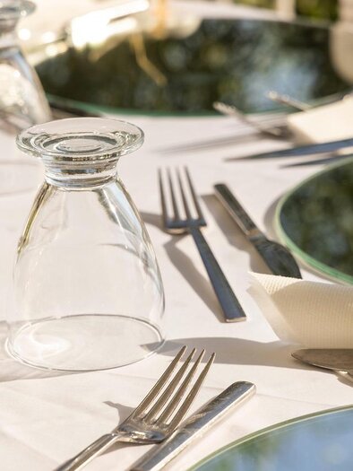 An elegantly set table with shimmering plates and cutlery. A glass carafe stands on the white tablecloth. | © Pixabay