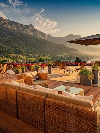 A cozy terrace with a view of the mountains and wide landscape. Wooden chairs and tables provide an inviting atmosphere for relaxation. | © Mondi Hotel