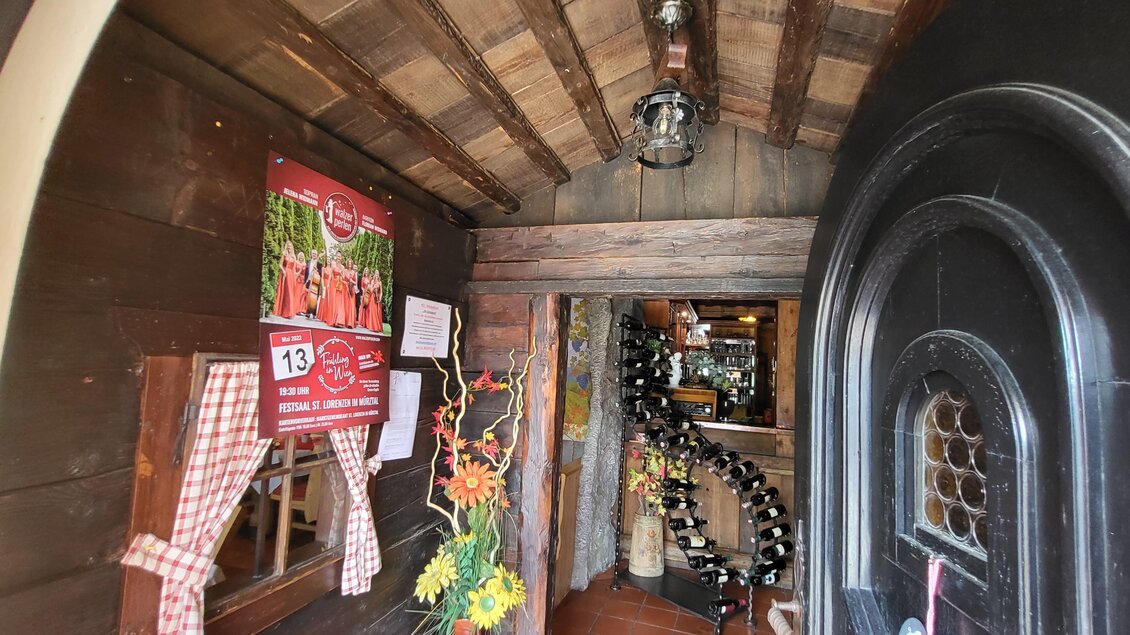 Ein gemütlicher Eingangsbereich mit Holzdekor und einer einladenden Atmosphäre. An der Wand hängen Dekorationen und Plakate. | © TV Hochsteiermark