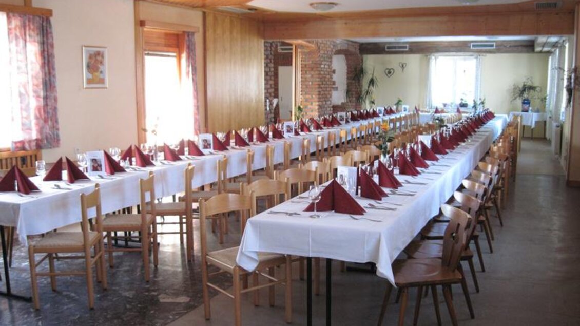 Ein festlich gedeckter Speisesaal mit langen Tischen und roten Servietten. Das Licht strömt durch die Fenster und sorgt für eine einladende Atmosphäre. | © Erlebnisregion Murtal