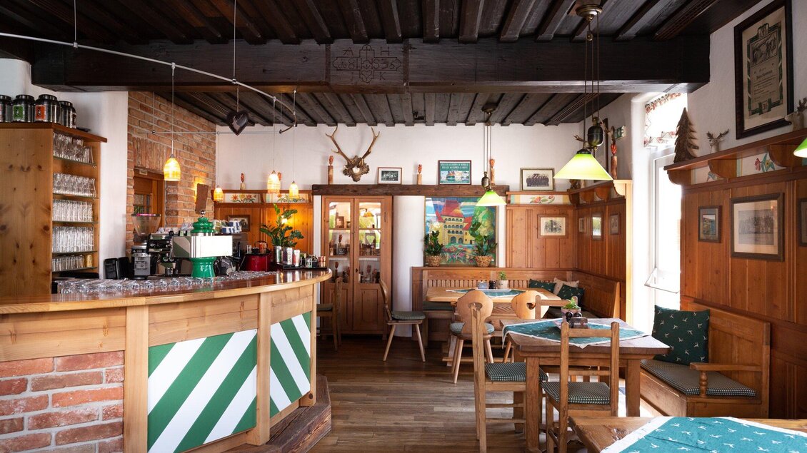 Ein gemütliches Restaurant mit Holzmöbeln und einer einladenden Bar. Die Wände sind mit dekorativen Bildern und antiken Gegenständen geschmückt. | © Geopho