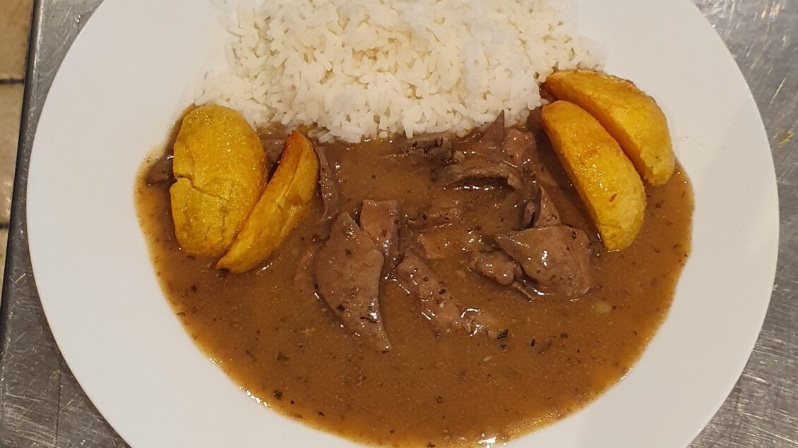 Ein Teller mit Reis, zartem Fleisch in einer braunen Sauce und gebratenen Bananen. Das Gericht ist auf einem weißen Teller angerichtet. | © Emil