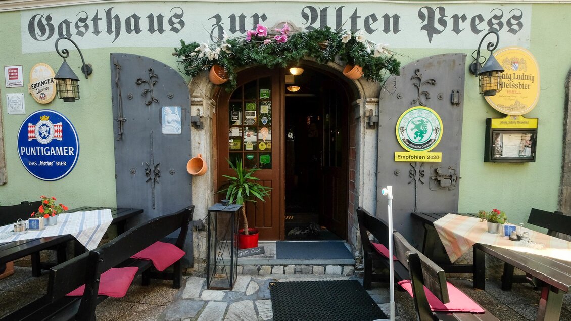 Ein gemütliches Gasthaus mit der Aufschrift „Gasthaus zur Alten Press“. Der Eingang ist mit Pflanzen und Dekoration geschmückt und es gibt Tische im Freien. | © Gasthaus zur Alten Press