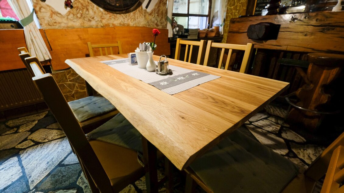 Ein rustikaler Tisch aus Holz steht in einem gemütlichen Raum. Um den Tisch herum sind mehrere Stühle angeordnet. | © Gasthaus zur Alten Press