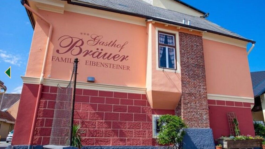 Ein Gasthof mit der Aufschrift „Gasthof Brüauer“ an der Wand. Das Gebäude hat eine ansprechende Farbgestaltung und einen gepflegten Außenbereich. | © Gasthof Bräuer