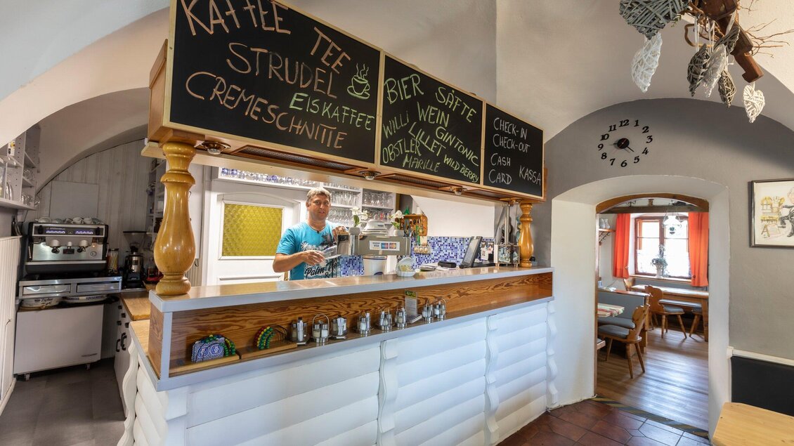 Ein einladendes Café mit einem freundlichen Barista hinter der Theke. Die Menütafel zeigt verschiedene Getränke und Snacks an. | © TV Region Graz - Lunghammer