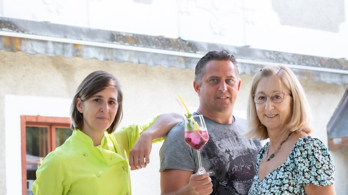 Drei Personen stehen zusammen und lächeln. Der Mann hält ein Getränk in der Hand, während die Frauen neben ihm posieren. | © TV Region Graz - Lunghammer