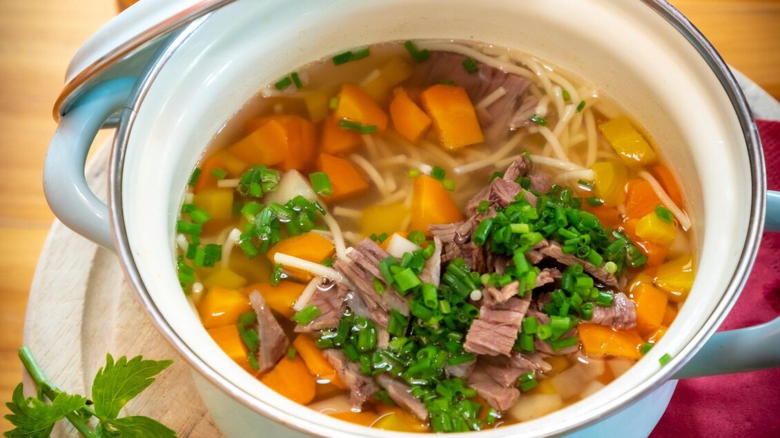 Ein Topf mit leckerer Suppe, der Rindfleisch, Karotten und Frühlingszwiebeln enthält. Die Brühe sieht klar und einladend aus. | © TV Region Graz - Lunghammer
