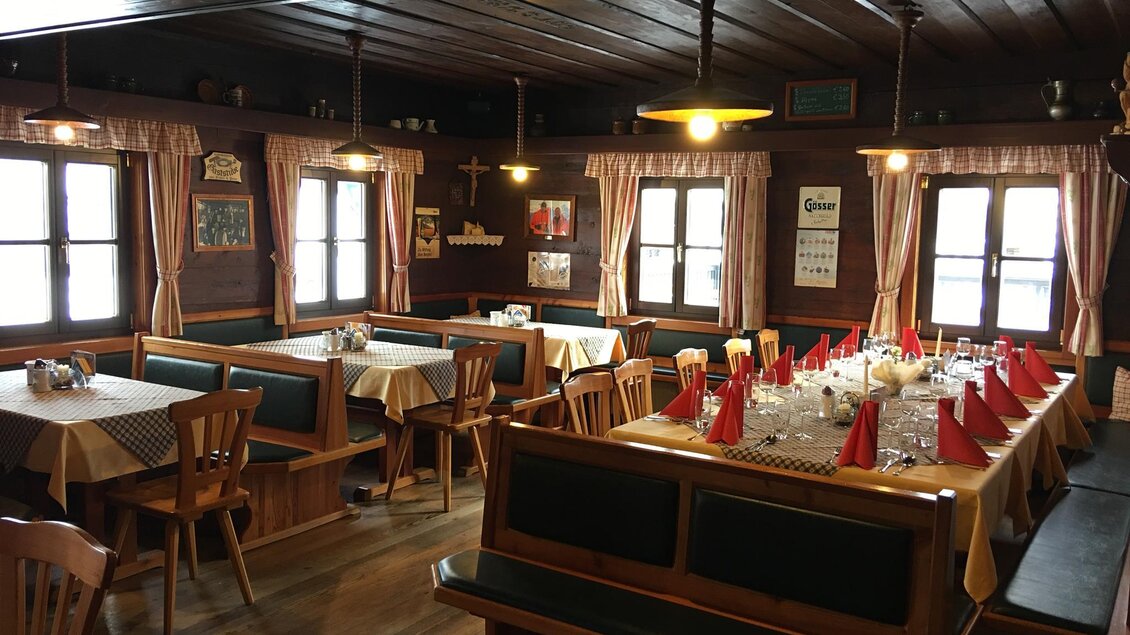 Ein gemütliches Restaurant mit Holzmöbeln und roten Servietten. Große Fenster sorgen für viel Tageslicht. | © Almgasthof Angerwirt