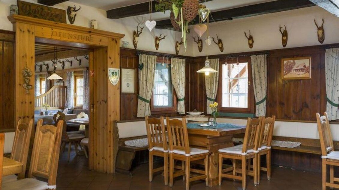 Ein gemütliches Restaurant mit Holzmöbeln und traditionellen Dekorationen. An den Wänden hängen Jagdtrophäen und das Ambiente ist einladend. | © Wassermann-Wirt