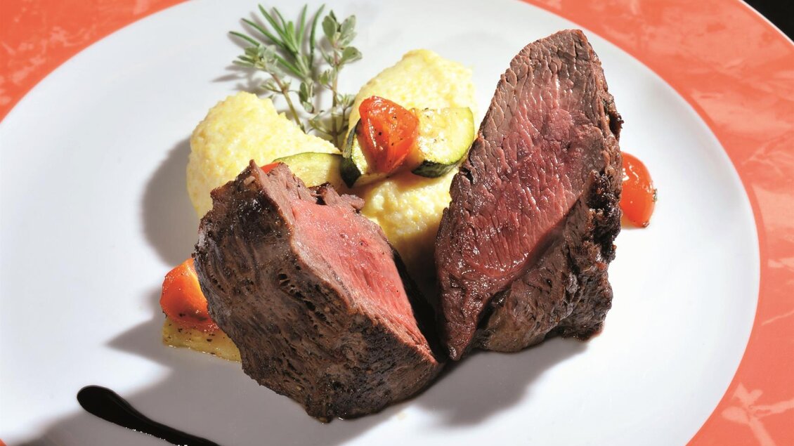 Ein elegantes Gericht mit zartem Fleisch, serviert mit pürierten Kartoffeln und Gemüsesorten. Das Ganze ist kunstvoll auf einem weißen Teller angerichtet. | © Gasthof BIOALM Wassermann-Wirt